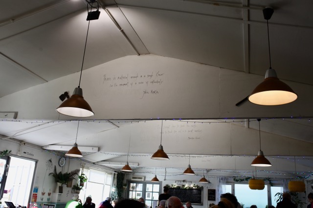 Cone shaped chandeliers hanging from the ceiling. Their are messages painted on the ceiling struts. 