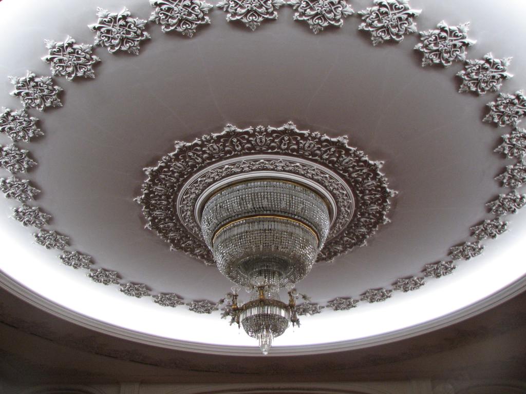 Close up of the chandelier which is surrounded by a large circular decorative moulding