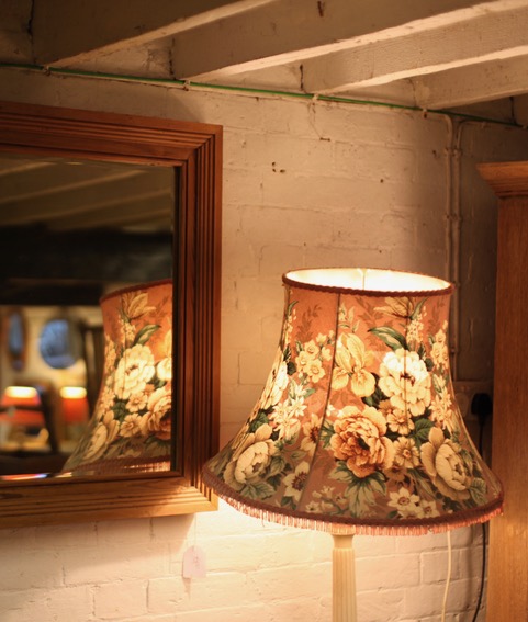 A chandelier covered in flowers and its reflection in a mirror.