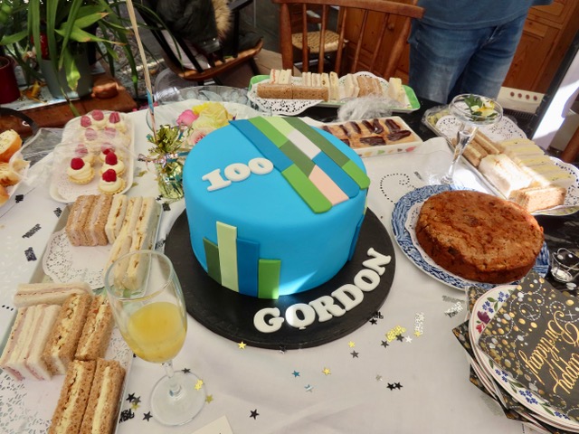Gordon's 100th birthday cake decorated in blue icing with coloured stripes. 
