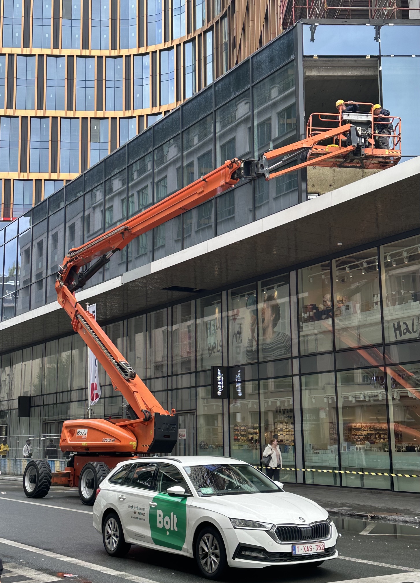 A machine with a fenced platform that lifts men up in order to wash the windows of high rise buildings.
