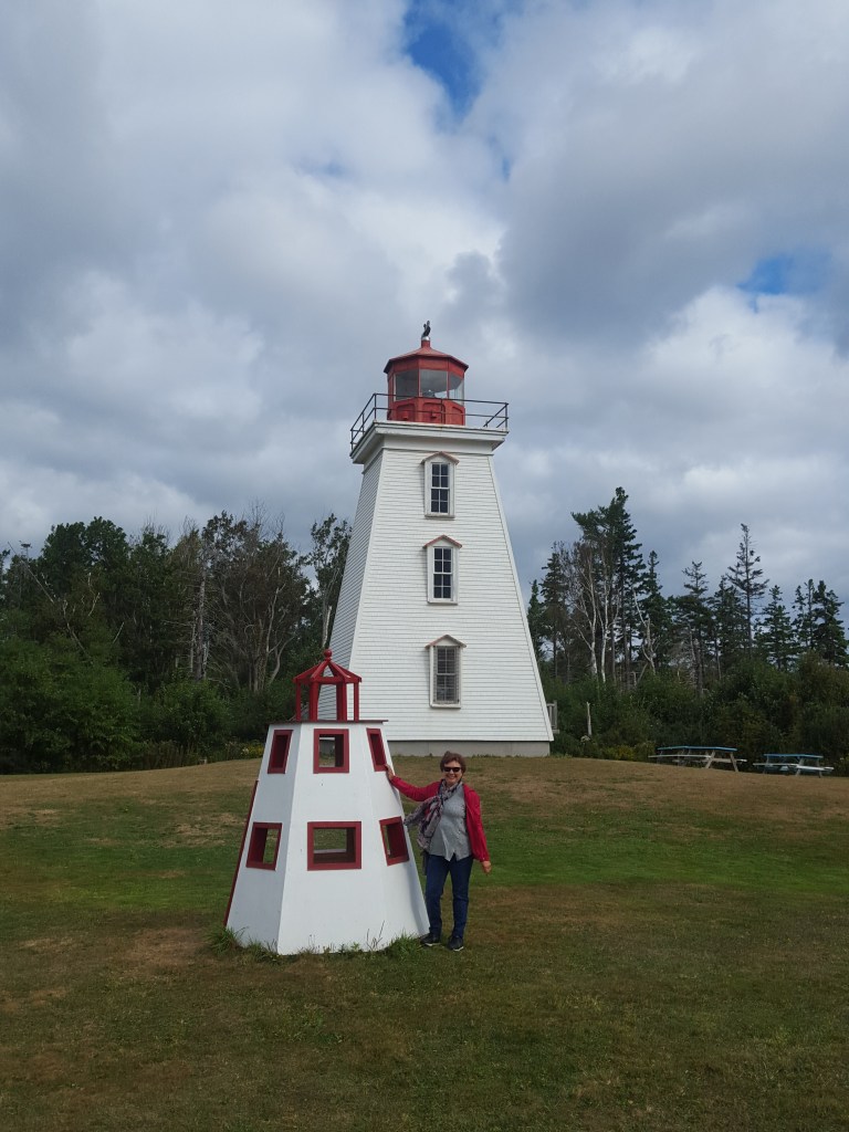 Photograph of Cape Bear Lighthouse and a smaller replica with Darlene Foster in the photograph.