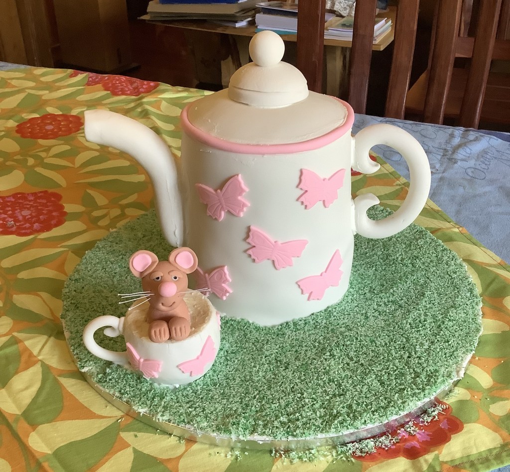 Robbie's white teapot cake with pink butterflies detail. A dormouse is peering out of the matching teacup. The teacup was very difficult to make. I filled it with bits of cake and used cream coloured icing to make it look like it was filled with tea.