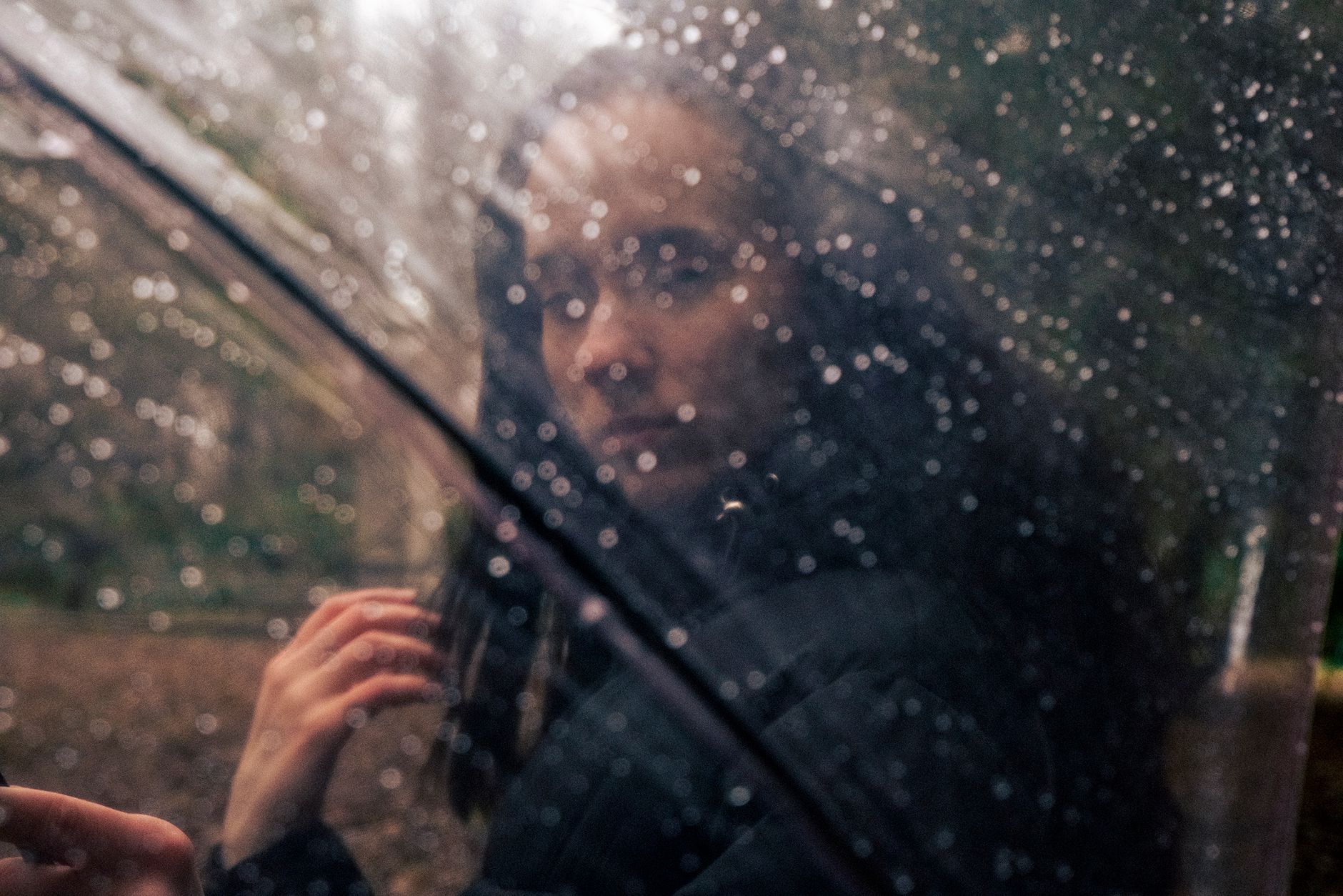 photo of a woman standing behind a transparent umbrella