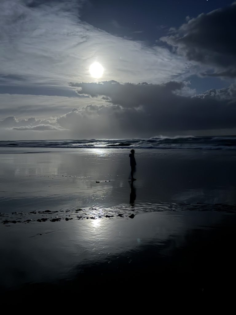 Boy on the beach at night during a full moon